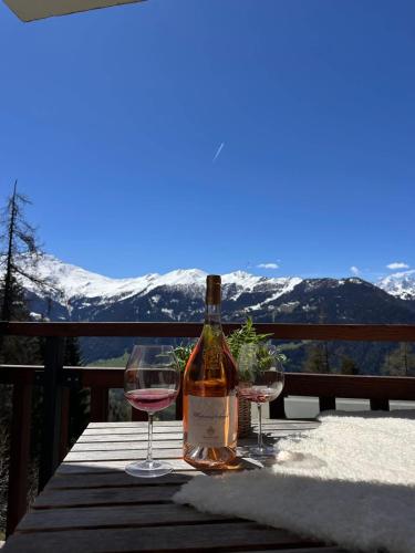 a bottle of wine and two glasses on a table at 3BR Central Pool Sauna Gym & Views in Verbier