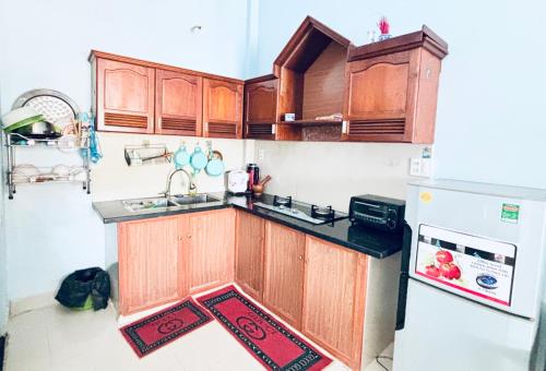 a kitchen with wooden cabinets and a sink and a refrigerator at Châu Gia Vỹ Dạ Hàn Mạc Tử in Thôn Lại Thê