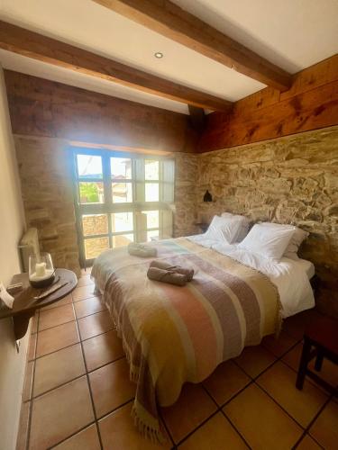 a bedroom with a large bed with a stone wall at The Pilgrim Stone - Vegan B&B in Rabanal del Camino
