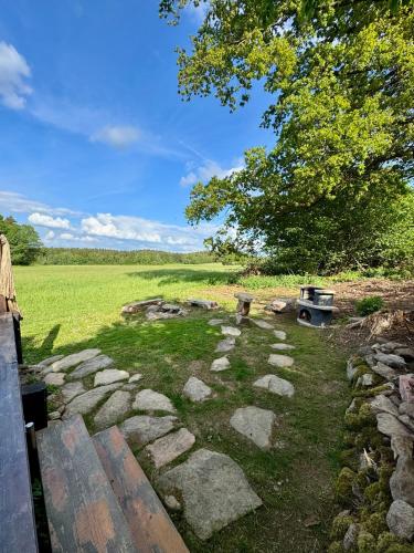 a garden with rocks and a tree and a field at Maringotka uprostřed divočiny in Proseč