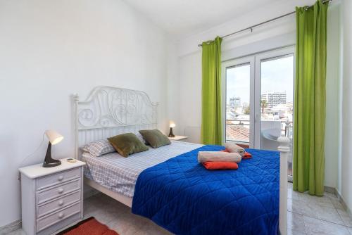a bedroom with a blue bed with green curtains at Marine Freestyler Glorious Terrace in Faro