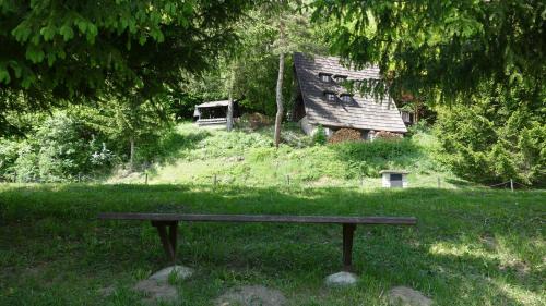 a bench sitting in the grass next to an old house at Chata Huslenky in Huslenky