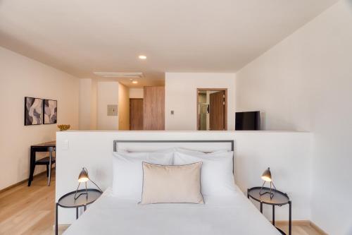 a bedroom with a white bed with two lamps at Nido x Downtown MTY in Monterrey