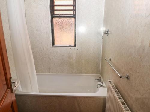 a bathroom with a bath tub and a window at Cabin No 5 - Salt and Fern Cabins in Port Talbot