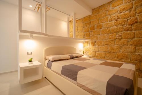 a bedroom with a bed and a brick wall at DaiRa 103 Luxury Suite sulle Mura di Cefalù in Cefalù