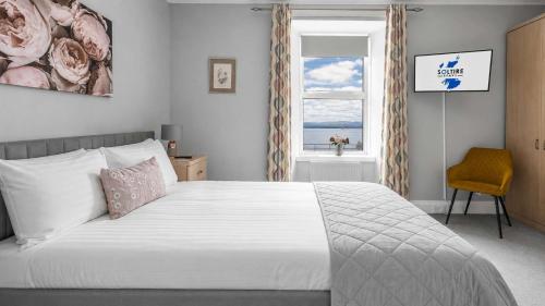 a bedroom with a bed with a window and a chair at Modern Apartment with Garden in Rothesay