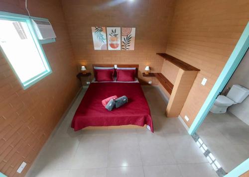 a small bedroom with a red bed with red pillows at Suite na Natureza com Café da Manhã in São Pedro