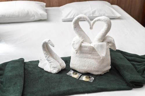 two towels shaped like swans sitting on a bed at Hotel Portela II - Av Principal e a 500m do Thermas dos Laranjais in Olímpia