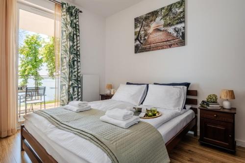 a bedroom with a bed with towels on it at Zegrze Lake Apartament VIRIDIAN z widokiem na jezioro, tarasem i parkingiem in Zegrze