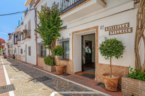 a building with trees in pots on a street at Marbella Village in Marbella