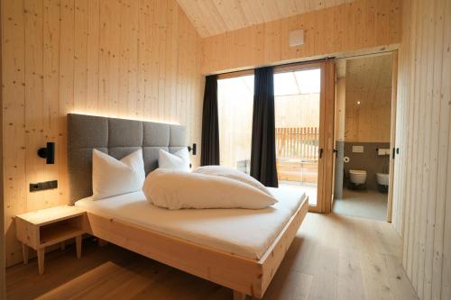 a bedroom with a bed and a large window at Preindlerhof Farmloft in Valle Di Casies