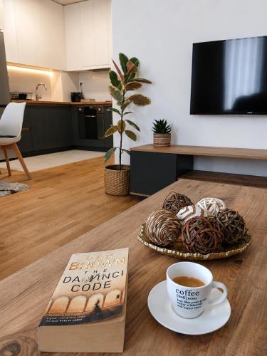 a table with a book and a cup of coffee and donuts at SOLU Luxury Apartments with Free Parking ,Fast Wi -Fi, New Building in Skopje