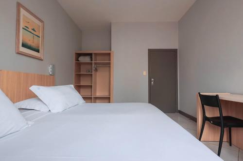 a bedroom with a large white bed and a desk at Hotel Sagres Praia in Balneário Camboriú
