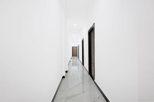 a hallway with white walls and marble flooring at Super Hotel O Antilia in Gorakhpur