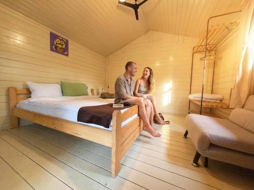 ein Mann und eine Frau sitzen auf einem Bett in einem Zimmer in der Unterkunft iVAVev Is'us in Eforie Sud