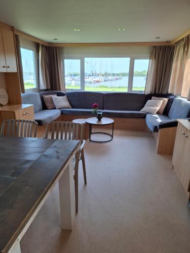 a living room with a couch and a table at Stacaravan met schitterend uitzicht over het meer, in Friesland! Op de 5-sterren Camping de Kuilart met Zwembad! in Koudum
