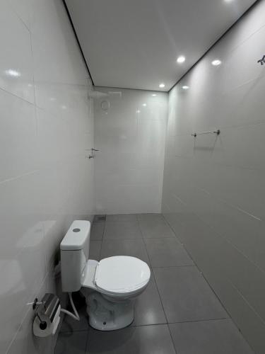 a white bathroom with a toilet in a room at Lotus in Gurupi