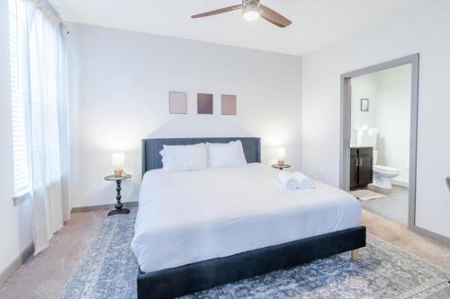 a white bedroom with a large bed and a ceiling fan at Warm, Inviting 2BD Apt In Matthews in Charlotte