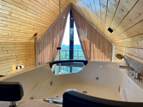 a bath tub in a room with a window at Les Pavillons D'Ehden in Ehden
