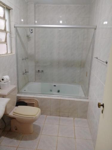 a bathroom with a shower and a toilet and a tub at Pousada Sant`Ana in Sabará