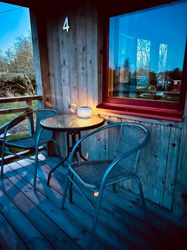 a table and chairs on a deck with a window at Klobbars Gästhem o Stugor in Kökar