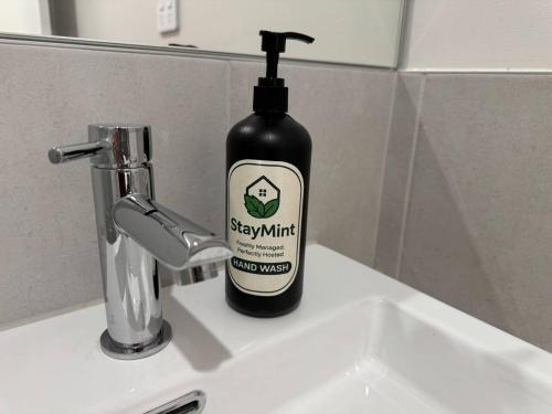 a bottle of soap sitting on top of a sink at Spacious New Home for 12 Guests in Campbelltown South