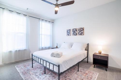 a white bedroom with a bed and a ceiling fan at Stylish, Comfortable 2BD Abode near DT Matthews in Charlotte