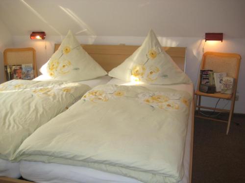 Una cama con sábanas blancas y almohadas. en Haus Bärbel, en Barlt
