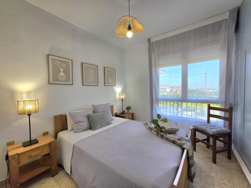 a bedroom with a bed and a window and a chair at Apartamento La Hojarada 20809 in Argoños