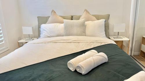 a bed with two towels sitting on top of it at Spacious New Home for 12 Guests in Campbelltown South
