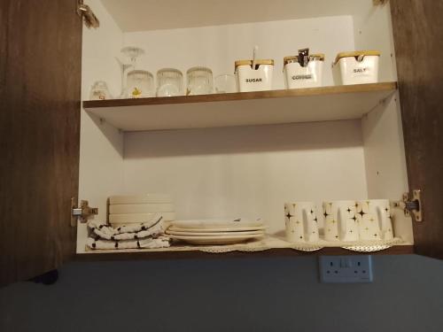 a shelf with plates and glasses on it at Executive 1bedroom Furnished and BnB apartment with GYM,Swimming pool,Cityview - Kitisuru ,Nairobi in Nairobi