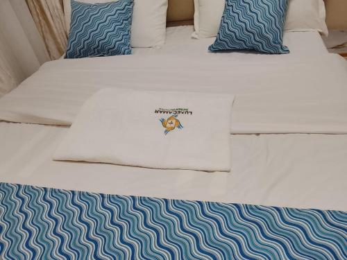 a bed with blue and white sheets and pillows at Executive 1bedroom Furnished and BnB apartment with GYM,Swimming pool,Cityview - Kitisuru ,Nairobi in Nairobi