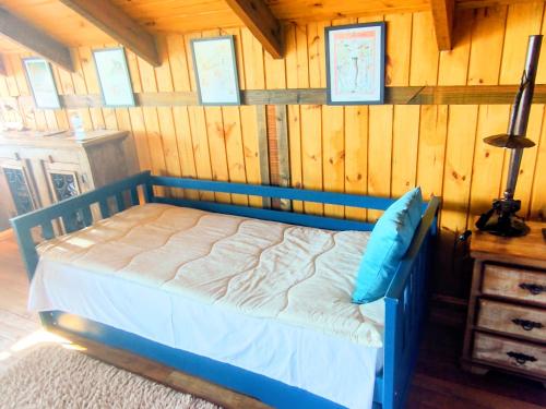 a bedroom with a blue bed in a wooden wall at Na'raucária in Cambará
