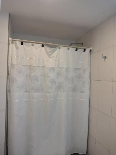 a shower with a white shower curtain in a bathroom at Hotel Alhambra in General Alvear