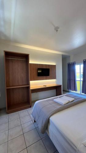 a bedroom with a bed and a desk and a tv at Pousada Village in Florianópolis