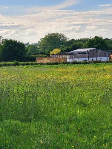 a field of green grass with a barn in the background at The Old Barn in Hanbury