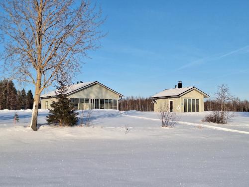 a house in a snow covered field with a tree at Paris Beach in Saarijärvi