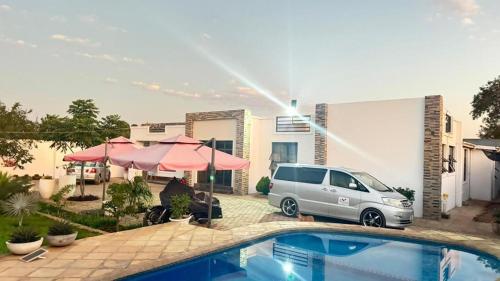 a white van parked next to a house with a pool at Kulala Holiday Home Livingstone in Livingstone