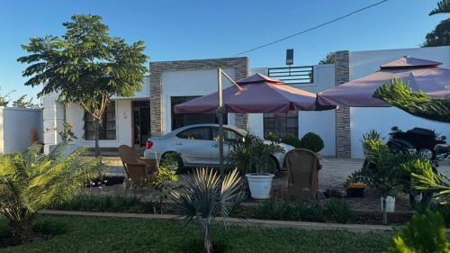 a car parked in front of a house with umbrellas at Kulala Holiday Home Livingstone in Livingstone