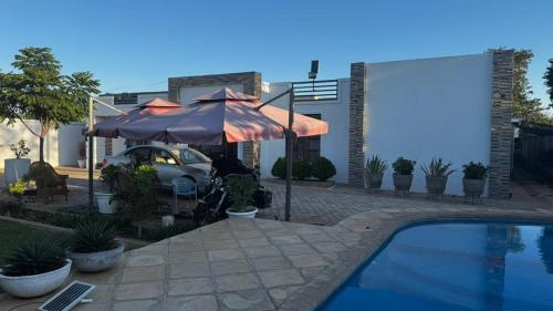 a patio with an umbrella and a swimming pool at Kulala Holiday Home Livingstone in Livingstone