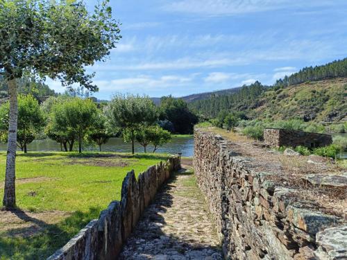 an old stone wall next to a river at Casa do Baloiço em Porto de Vacas Aldeias de Xisto in Janeiro de Baixo