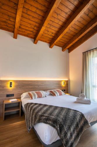two beds in a room with wooden ceilings at Casas Green Ordesa in Aínsa