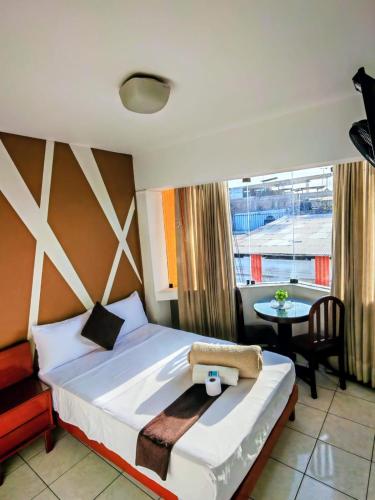 a bedroom with a bed and a table and a window at Silvana Hostal in Chiclayo