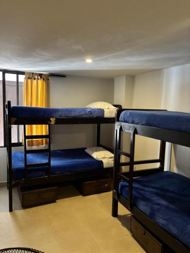 a room with three bunk beds with blue sheets at Casa Kiwi Hostel in Medellín