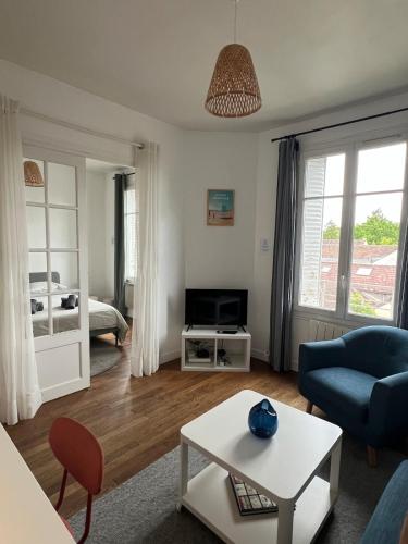 a living room with a blue couch and a bed at Le Clair Bellifontain in Fontainebleau