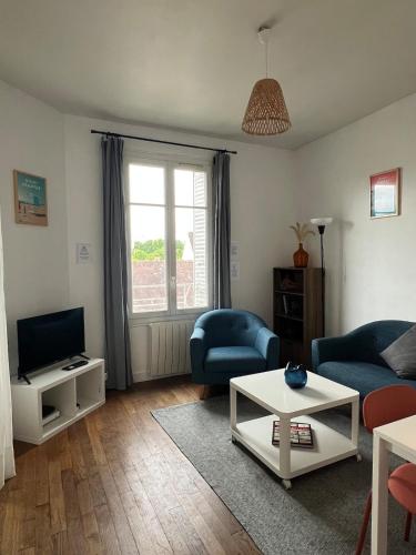 a living room with a couch and a tv at Le Clair Bellifontain in Fontainebleau