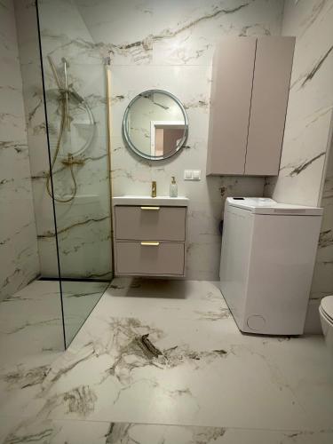 a white bathroom with a sink and a mirror at Kaszmirowy Apartament in Mrągowo