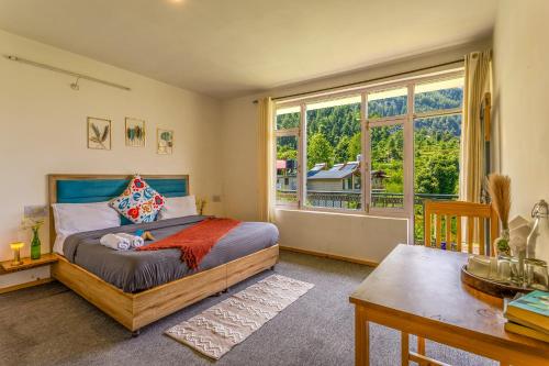 a bedroom with a bed and a table and a window at La Heim Hostels in Manāli
