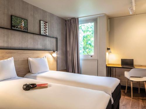 a hotel room with two beds and a desk at ibis Paris Gennevilliers in Gennevilliers