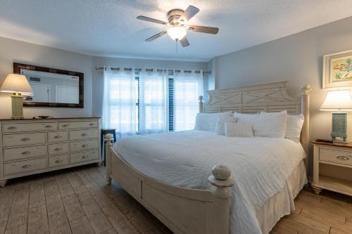 a bedroom with a white bed with a ceiling fan at Harbour Place 510 in Gulf Shores